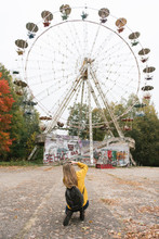 Woman Taking Photo Of Abandoned Ferris Wheel