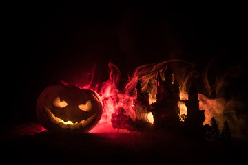 Horror view of Halloween pumpkin with scary smiling face. Head jack lantern with spooky building