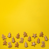 Fototapeta Psy - Homemade christmas cookies on yellow background with copy space. Square crop. Pattern of gingerbread men, snowflake, star, fir-tree, boot shapes. New year concept