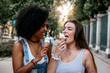 © santypan - Beautiful women eating one ice cream in the street.