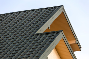 Wall Mural - Close-up detail of new modern house top with shingled green roof on clear blue sky background. Professionally done building and construction work, real estate property, contract concept.