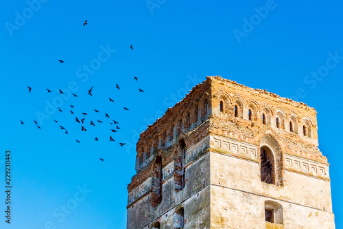 Fotografiet Tower of the ancient castle against the blue sky with birds_