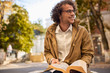 © iuricazac - Happy young man with glasses reading and posing with book outdoors. College male student carrying books in campus in autumn street. Smiling guy wears spectacles and curly hair reading books outside