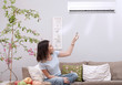 woman using remote control for air conditioner