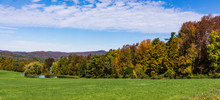 View Of Meadow And Pond With Hills And Mountains Dressed In Bright Autumn Colors Of Fall Foliage 