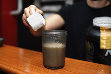 sport, fitness, healthy lifestyle and people concept - close up of man with jar and bottle preparing protein shake