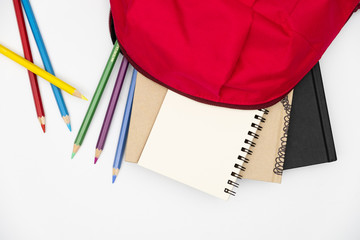 Top view- backpack and school stationery on white background