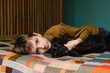 © Rebecca Spencer/Stocksy - Portrait of boy with his puppy lying on bed at home