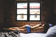 © Christian Tisdale/Stocksy - A young woman laying uncovered on a bed in only underwear