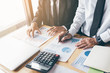 © wutzkoh - Two business people calculate finance analysis graph report in the office room.