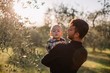 © Liliya Rodnikova/Stocksy - Father holding his son on arms in sunset olive garden