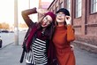 © opolja - Outdoors fashion portrait young pretty best girls friends in friendly hug. Walking at the city. Posing at the street. Wearing stylish outerwear and hats. Bright make up. Positive emotions.