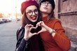 © opolja - Outdoors fashion portrait young pretty best girls friends in friendly hug. Walking at the city. Posing at the street. Wearing stylish outerwear and hats. Bright make up. Positive emotions.
