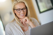 © goodluz - Portrait of blond woman with eyeglasses working on laptop