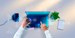 © AndSus - Hands of developer working on keyboard of laptop on white desk. top view. Workplace of programmer with notebook, table plant, smartphone, icons and interface elements.