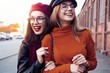 © opolja - Outdoors fashion portrait young pretty best girls friends in friendly hug. Walking at the city. Posing at the street. Wearing stylish outerwear and hats. Bright make up. Positive emotions.