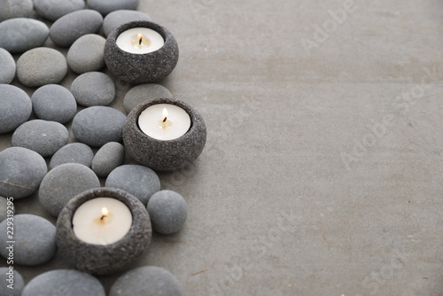 Three candle with pile of gray stones on gray background Lerretsbilde