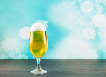 Goblet Style Beer Glass On Dark Natural Wooden Table With Light Blue Bokeh Background. 