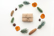 Composition with christmas gift in craft paper, dried orange and mandarin, anise stars, cinnamon, pine cones, fir branches on white background. Flat lay, top view
