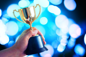 Wall Mural - winner hold trophy with bokeh blue light glowing background