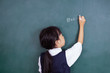 Leinwandbild Motiv Asian Chinese little girl writing on blackboard