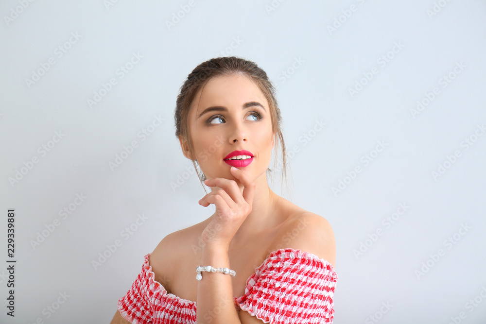 Beautiful young woman on light background