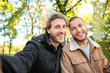 Happy gay couple taking selfie in park