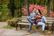 © Pixel-Shot - Loving young couple sitting on wooden bench in autumn park