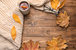 Composition with cup of aromatic tea, warm plaid and autumn leaves on wooden background