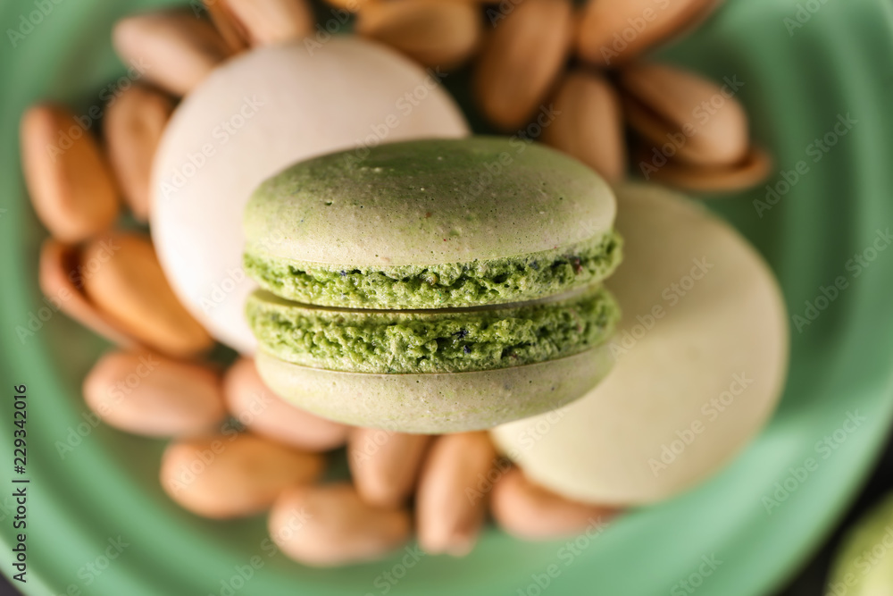 Plate with sweet macaroons and pistachio nuts, closeup