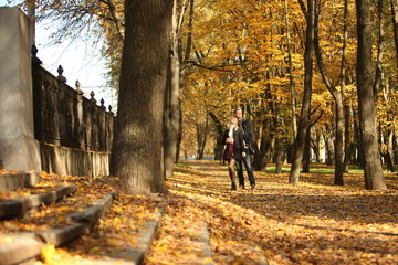 Wall Mural - couple people young man and women walking autumn park fanny sunny day