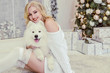 © domarevatanya - beautiful blonde in white clothes with a white husky on the background of the fireplace and Christmas tree.