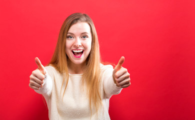 Wall Mural - Happy young woman giving thumbs up on a solid background