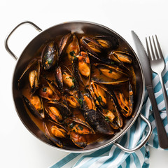 freshly cooked mussels in a frying pan in tomato sauce. pepata di cozze or mussels marinara. classic dish of mediterranean italian cuisine . isolated on white