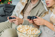 © LIGHTFIELD STUDIOS - cropped shot of couple with popcorn playing video games together on couch at home
