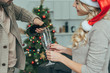 © LIGHTFIELD STUDIOS - cropped shot of young couple pouring champagne into glasses in front of christmas tree at home