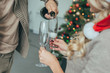 © LIGHTFIELD STUDIOS - cropped shot of couple pouring champagne into glasses in front of christmas tree at home