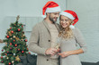 © LIGHTFIELD STUDIOS - happy young couple with champagne glasses in front of christmas tree at home