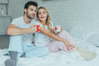 © LIGHTFIELD STUDIOS - beautiful young couple with cups of cocoa sitting in bed at home