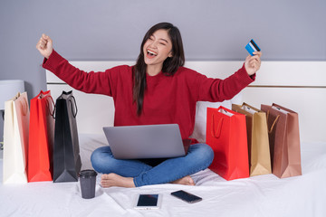 Sticker - cheerful woman using laptop computer to shopping online on bed