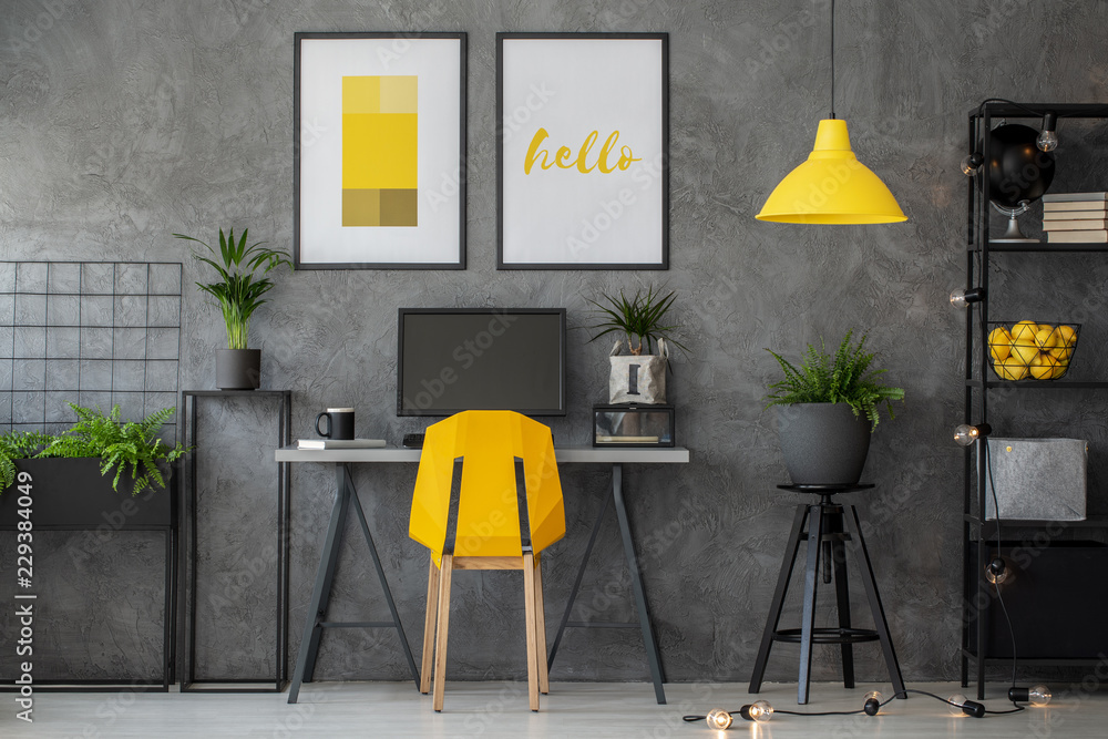 Stylish yellow and grey home office with industrial furniture and urban jungle, real photo with posters on concrete wall - obrazy, fototapety, plakaty 