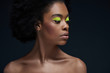 © LIGHTFIELD STUDIOS - portrait of beautiful african american model with bright neon makeup and bare shoulders isolated on black