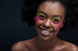 © LIGHTFIELD STUDIOS - portrait of cheerful african american model with bright neon makeup posing isolated on black
