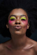 © LIGHTFIELD STUDIOS - portrait of african american model with bright neon makeup isolated on black, air kiss