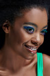 © LIGHTFIELD STUDIOS - portrait of smiling african american model with bright blue eyes shadows isolated on black
