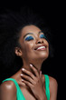 © LIGHTFIELD STUDIOS - portrait of smiling african american model with bright blue eyes shadows isolated on black