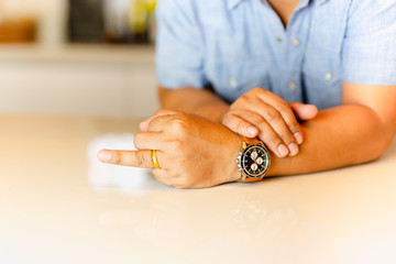 Man pointing his ring finger with gold wedding ring on his finger.