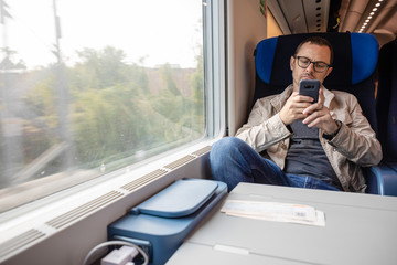 Middle age man looking out of the window of train. Passenger during travel by high speed express train in Europe