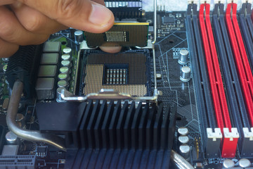 Close up hand of technician putting CPU on the socket of computer motherboard