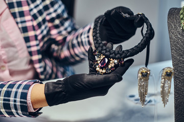 Wall Mural - Close-up photo of a jewelry worker presenting a costly necklace with gemstones in a jewelry store.